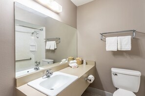 Un baño de hotel con lavamanos, espejo, inodoro y toallero.