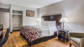 A hotel room with a bed, bedside tables, a desk, a chair, and a wardrobe.