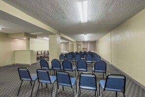 A conference room with rows of chairs, a podium, and a carpeted floor.