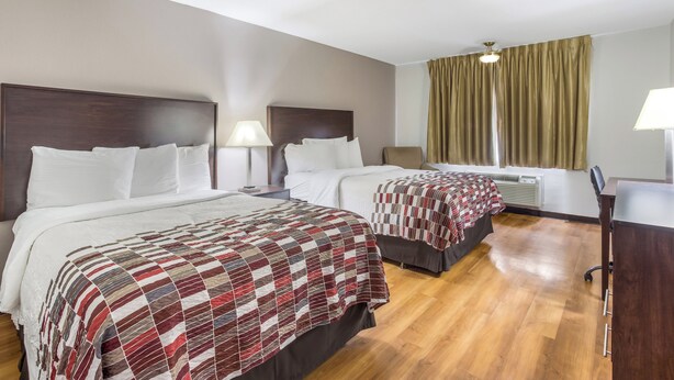 A hotel room with two beds, a desk, and a chair. - Red Roof Inn Meridian (Meridian)