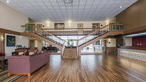 A spacious lobby with a central staircase, wooden flooring, and a reception desk. - Red Roof Inn Meridian (Meridian)