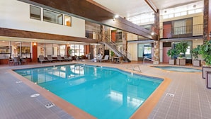 An indoor swimming pool with a tiled floor, a staircase, and lounge chairs. - Best Western Plus Weston Inn (Logan)