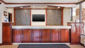 A kitchen with a built-in TV, wooden cabinets, and a patterned backsplash. - Best Western Plus Weston Inn (Logan)