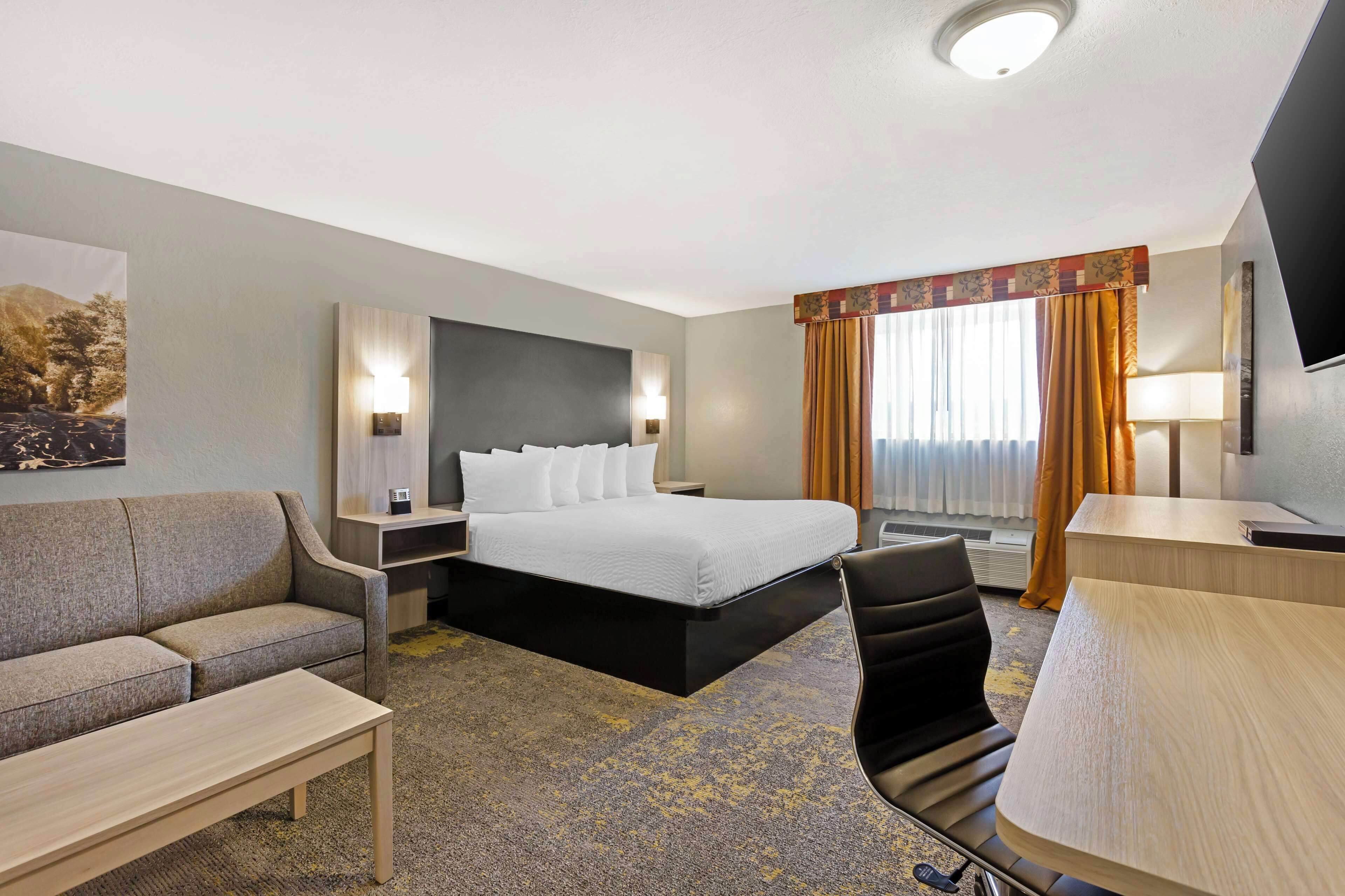 Een hotelkamer met een bed, een slaapbank, een bureau en een televisie.
