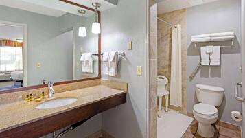 A bathroom with a double sink, a large mirror, a shower, and a toilet.