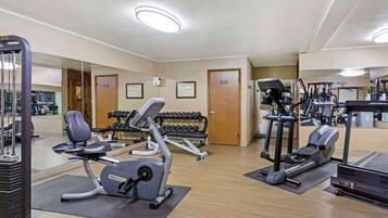 Une salle de sport équipée de machines de cardio, de bancs de musculation et d’haltères.