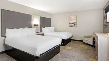 A hotel room with two beds, a desk, a chair, and a painting on the wall.