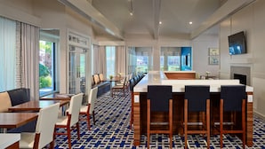 A modern hotel lobby with a long reception desk, seating area, and large windows offering views of greenery. - Siegel Select Oklahoma City (Oklahoma City)