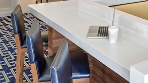 A modern hotel lobby with a long reception desk, multiple seating areas, and a wooden accent wall. - Siegel Select Oklahoma City (Oklahoma City)