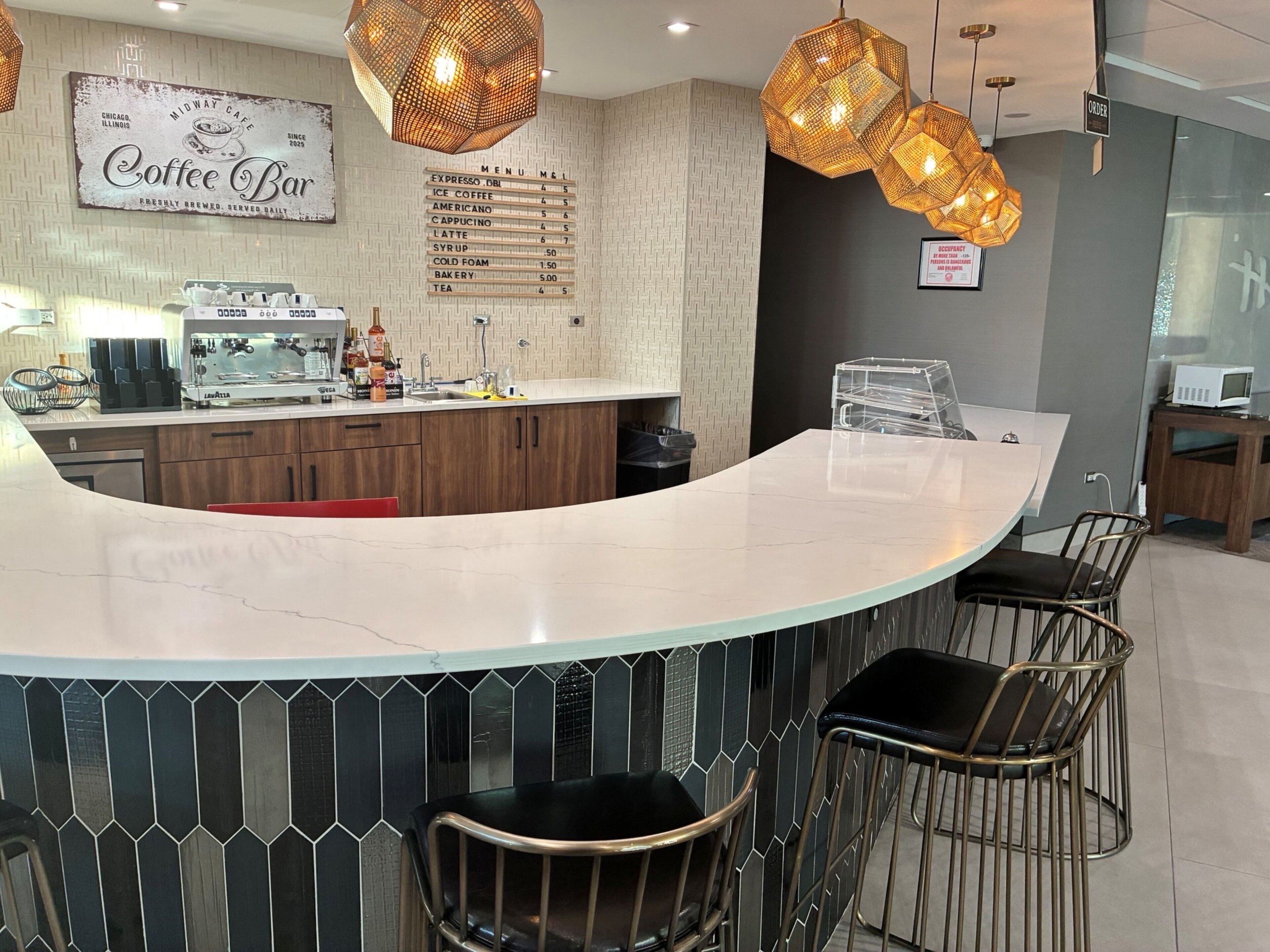 A modern coffee bar with a menu board, barista station, and seating area.