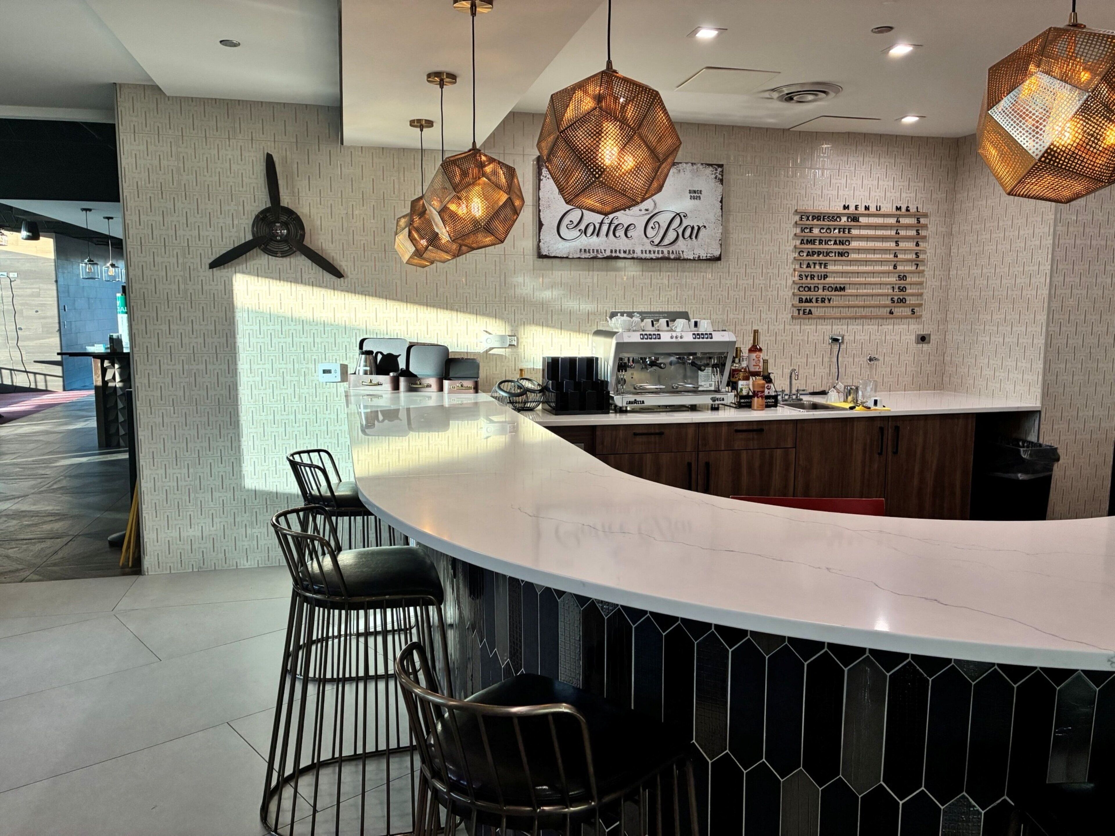 A modern coffee bar with a bar counter, seating area, and a menu board.