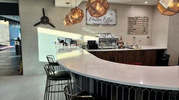 A modern coffee bar with a bar counter, seating area, and a menu board.