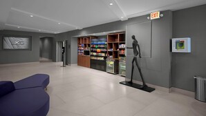 Un hall d’entrée moderne avec un distributeur automatique, une statue et un panneau indiquant la sortie.