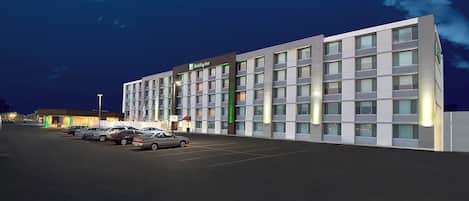 Un hotel Holiday Inn con un estacionamiento y varios coches aparcados frente a él.