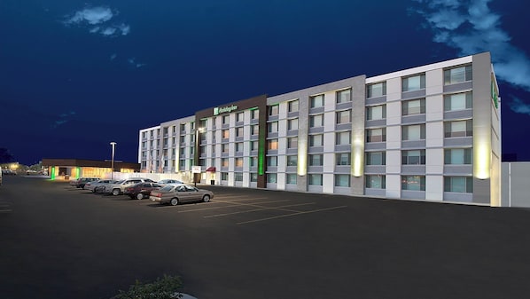 Un hotel Holiday Inn con un estacionamiento y varios coches aparcados frente a él.
