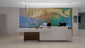 Un comptoir d’accueil agrémenté d’un mur en mosaïque, d’un écran numérique et d’un panneau indiquant les commodités disponibles, comme les toilettes et une salle de réunion.
