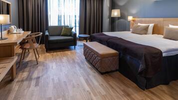 Una habitación de hotel con una cama grande, un escritorio con una silla, un sofá y una pequeña mesa.