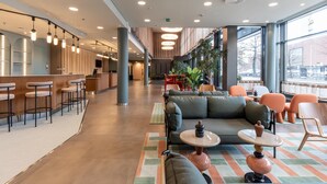 Eine moderne Lobby mit Barbereich, Sitzgelegenheiten und großen Fenstern.