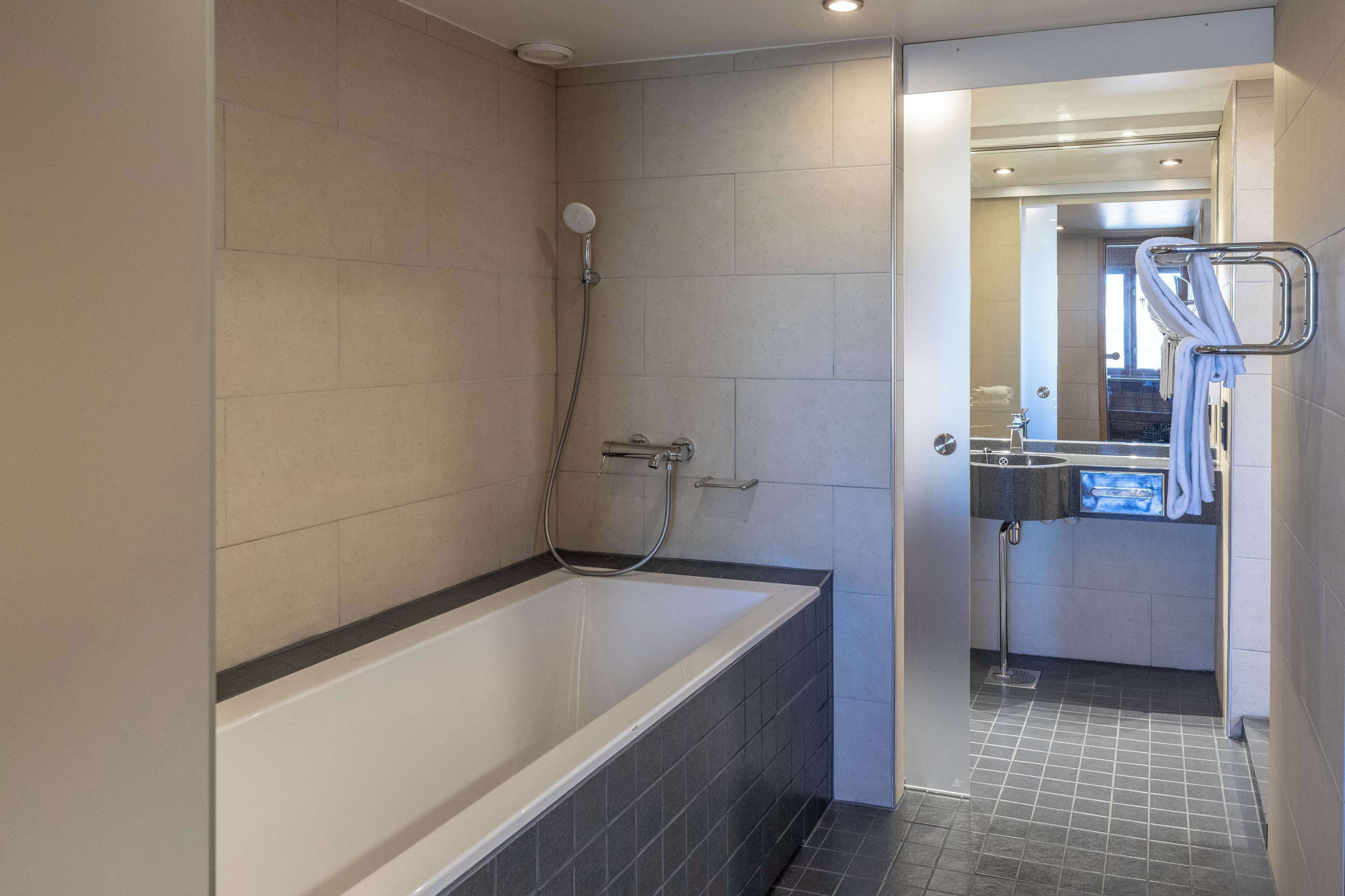 Ein modernes Badezimmer mit Badewanne, Dusche und Handtuchhalter.