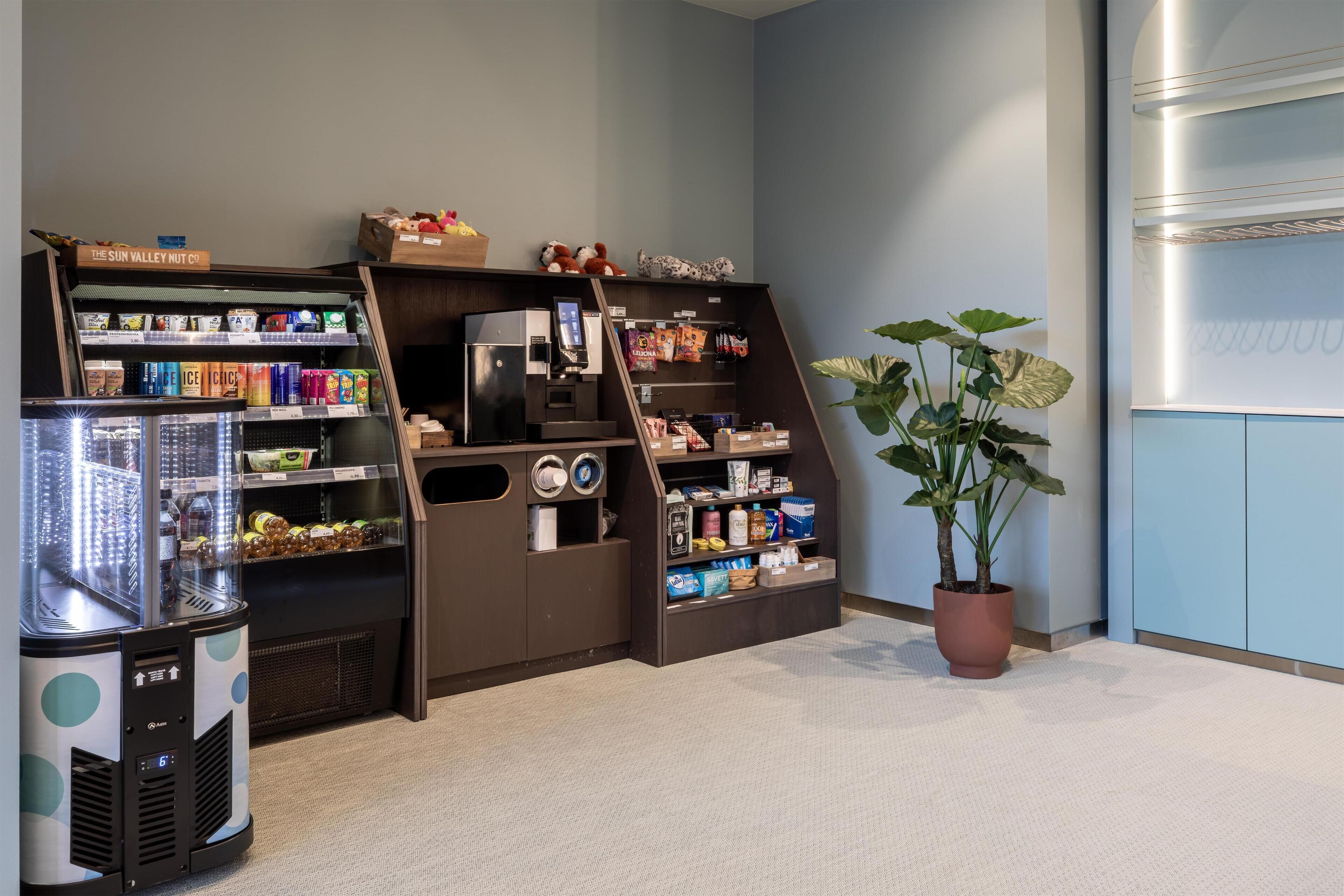 A vending machine, a coffee machine, and a plant in a hotel lobby.