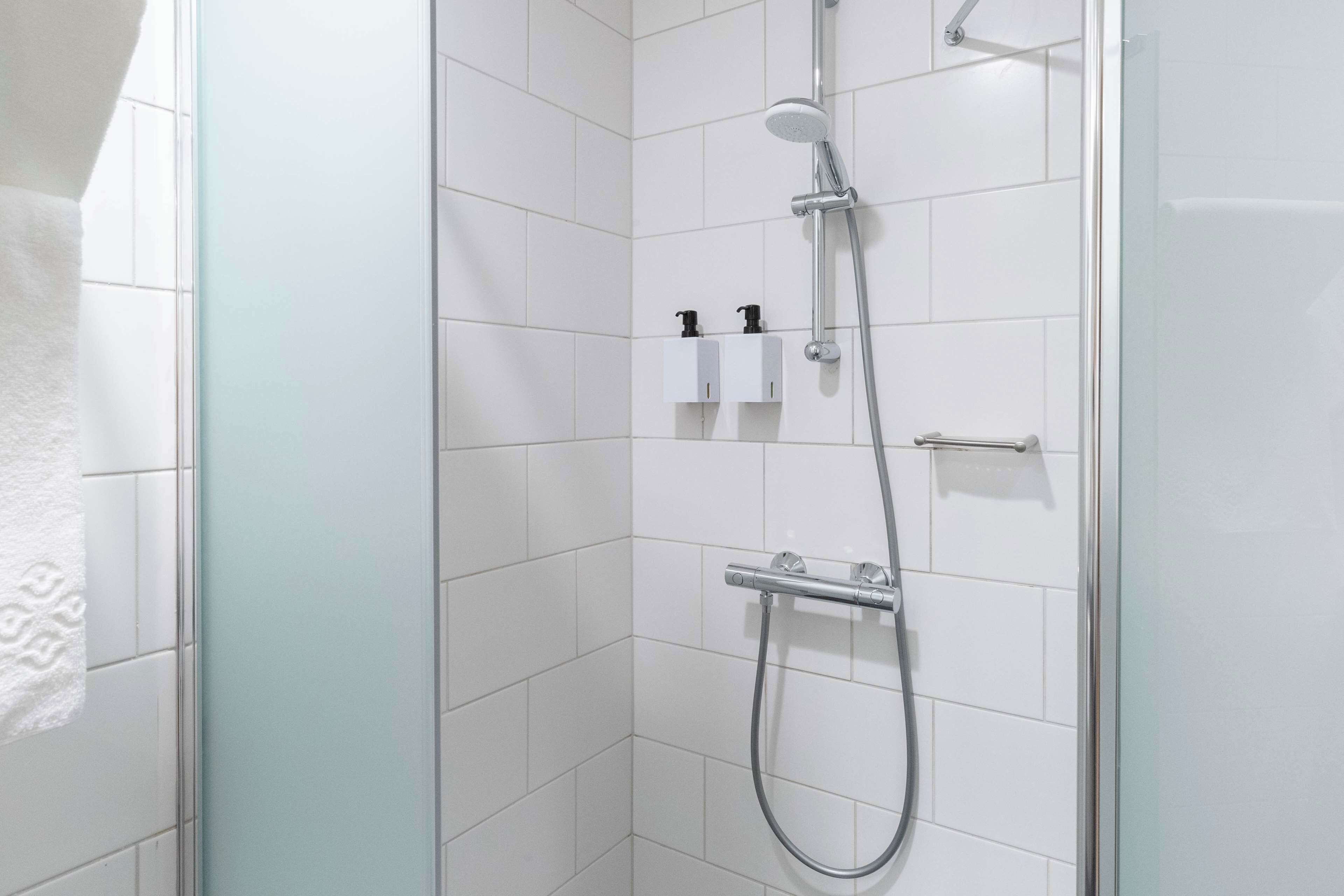A modern shower with a handheld showerhead and a handheld hose.