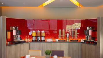 A modern kitchen with a red backsplash, stainless steel appliances, and a dining area with a table set for two.