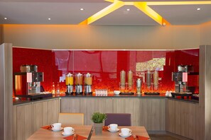 A modern kitchen with a red backsplash, stainless steel appliances, and a dining area with a table set for two.