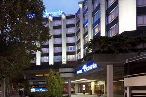 A multi-story hotel with a prominent 'Oceania' sign, featuring a modern architectural design with balconies and large windows.
