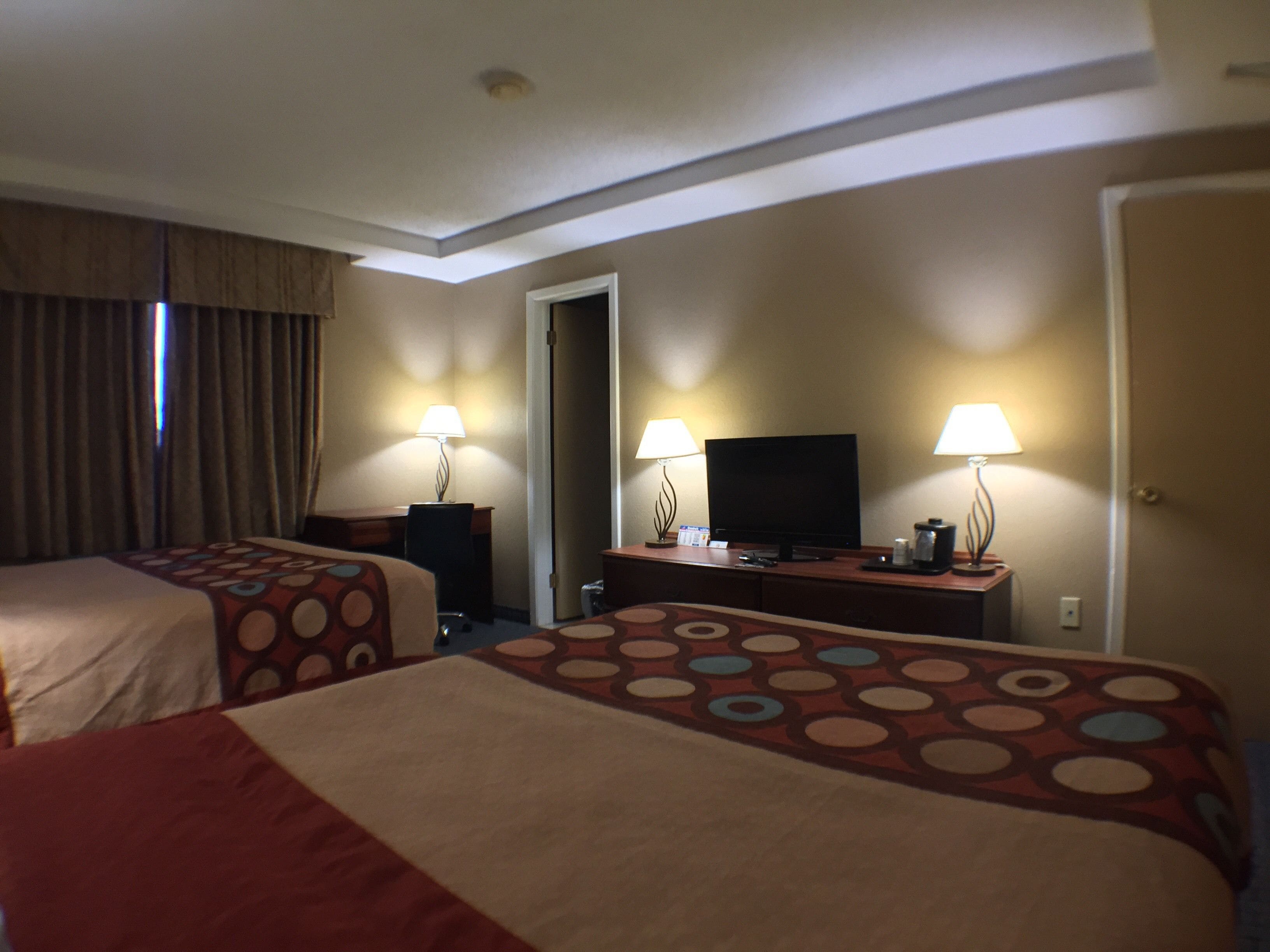 Une chambre d’hôtel avec deux lits, un bureau, une télévision et deux lampes.