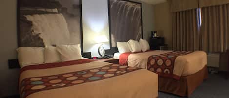Habitación de hotel con dos camas, un cuadro grande en la pared, una lámpara y una ventana con cortinas.