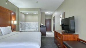 Une chambre d’hôtel avec un grand lit, une télévision, un bureau et une salle de bain dont un des murs est recouvert de marbre.