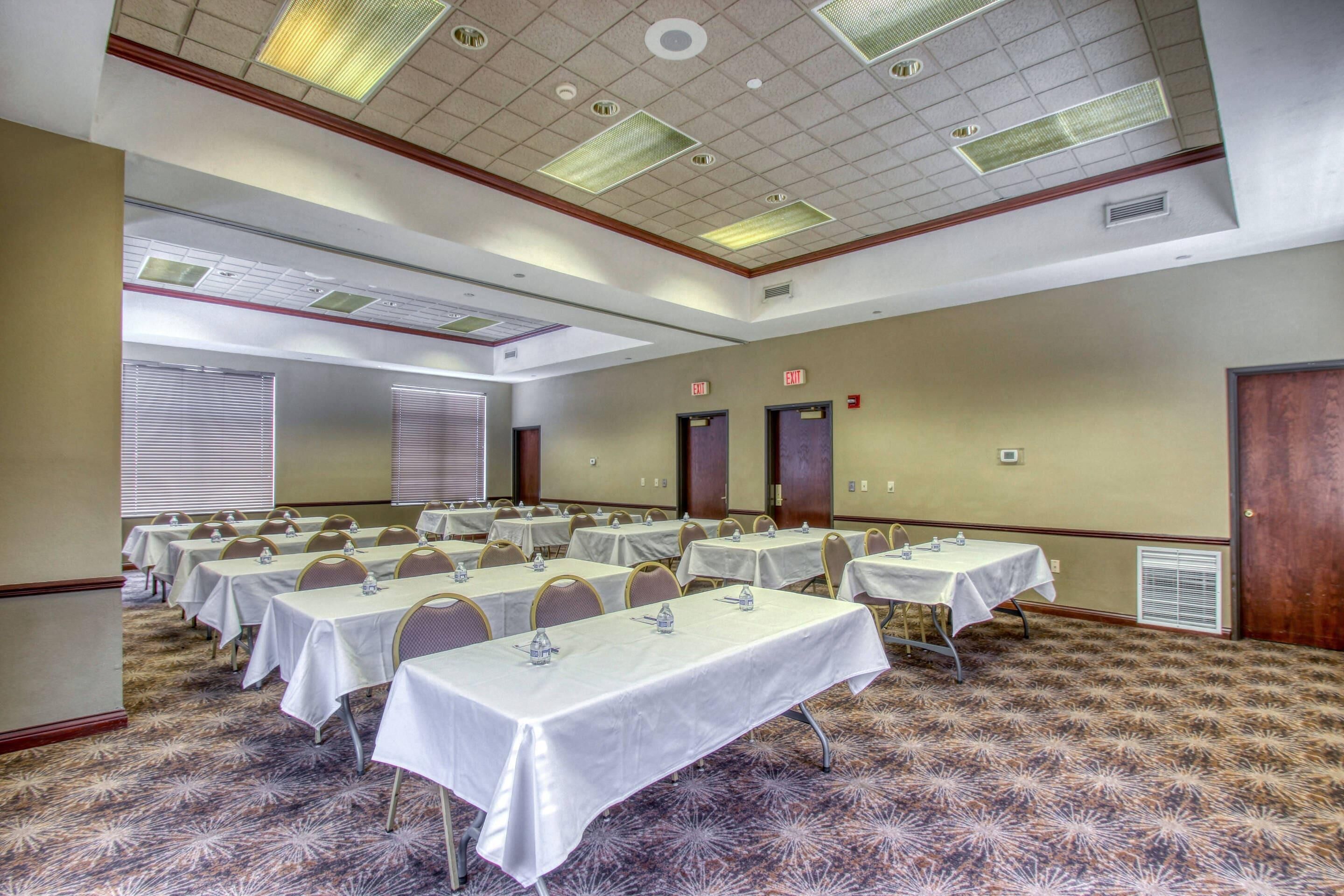 A conference room with multiple tables, chairs, and a carpeted floor.