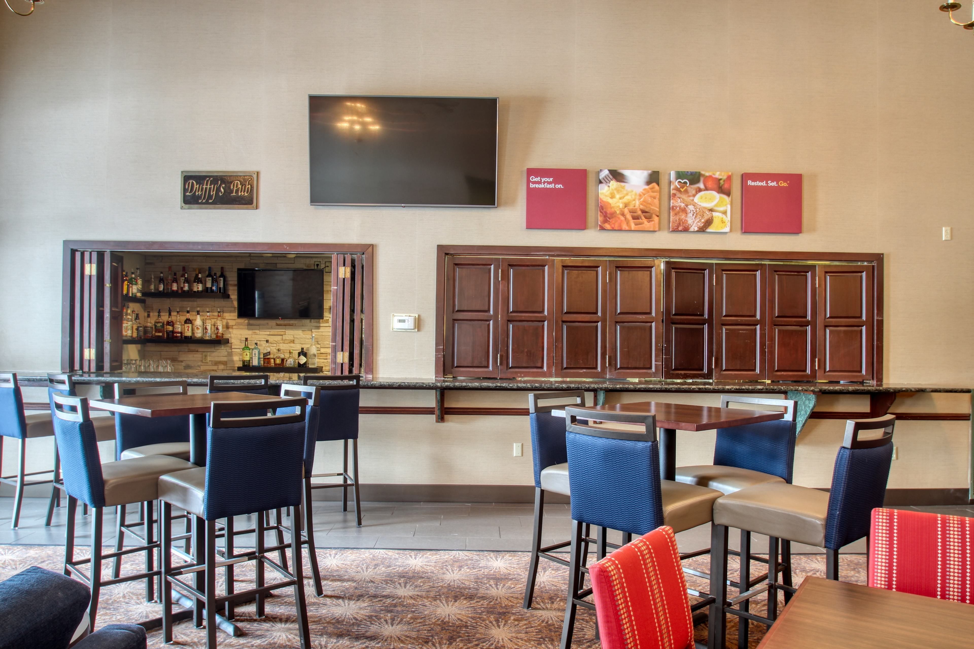 A bar area with a television, bar stools, and a sign reading "Duffy's Pub".