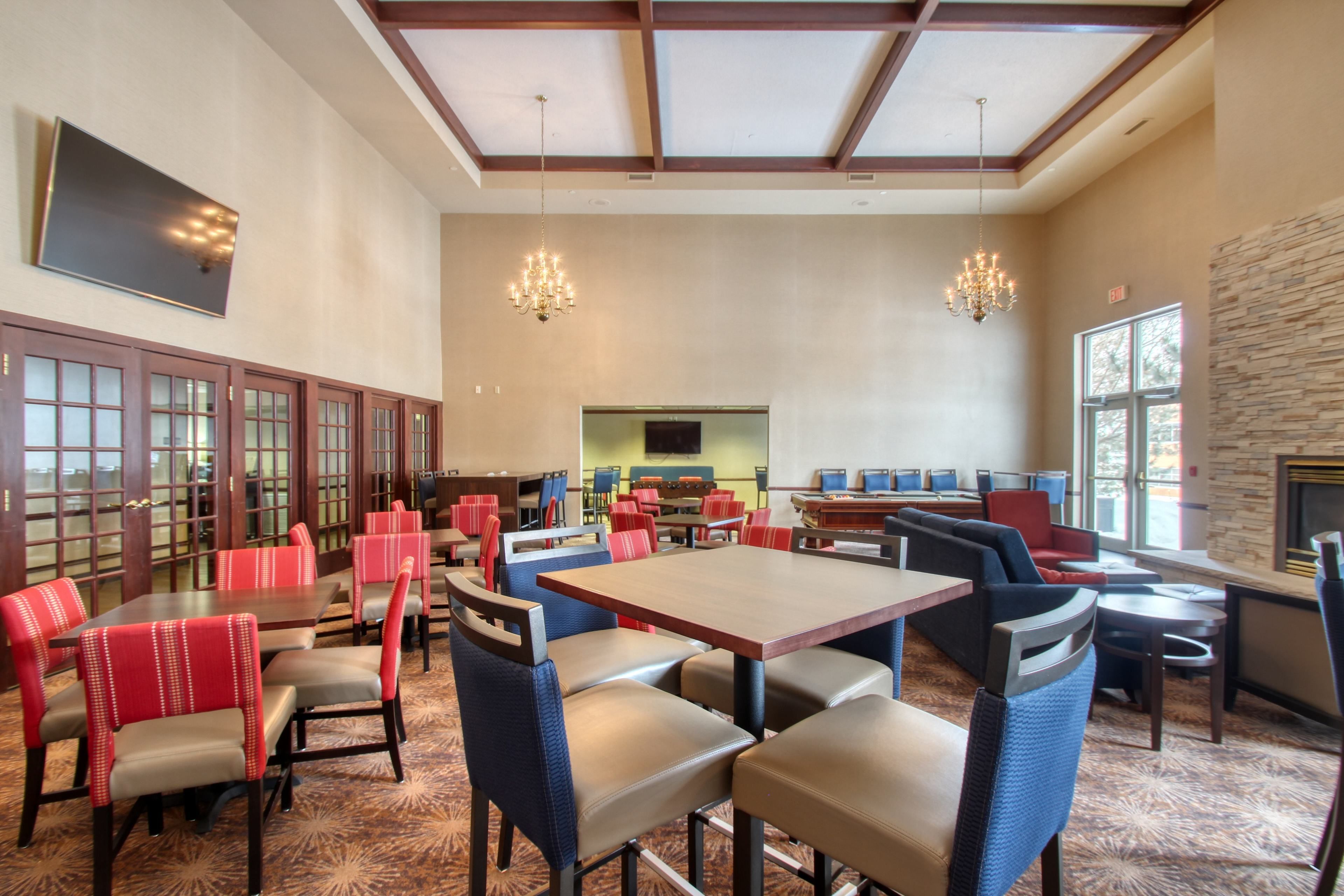 A spacious dining area with high ceilings, chandeliers, and a mix of booth and table seating.