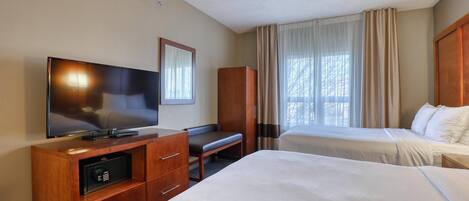 A hotel room with a TV, a desk, two beds, and a wardrobe.