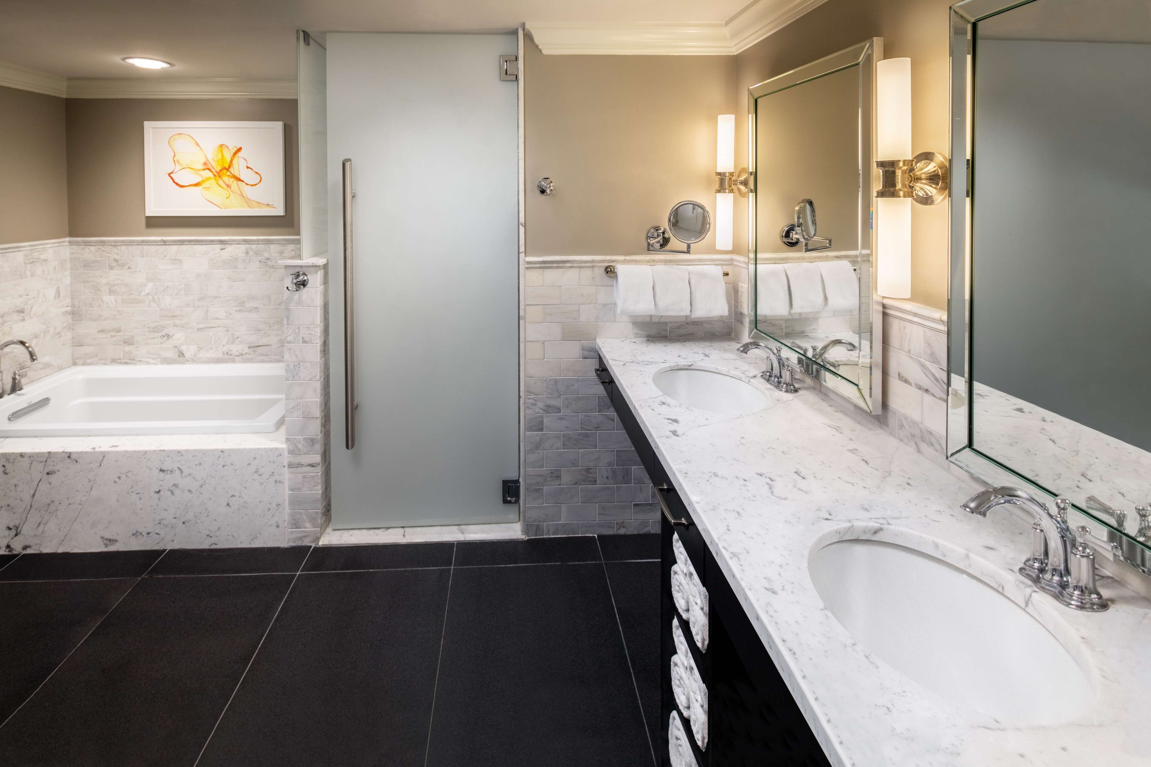 Un baño moderno con dos lavamanos, una bañera y una cabina de ducha de cristal.