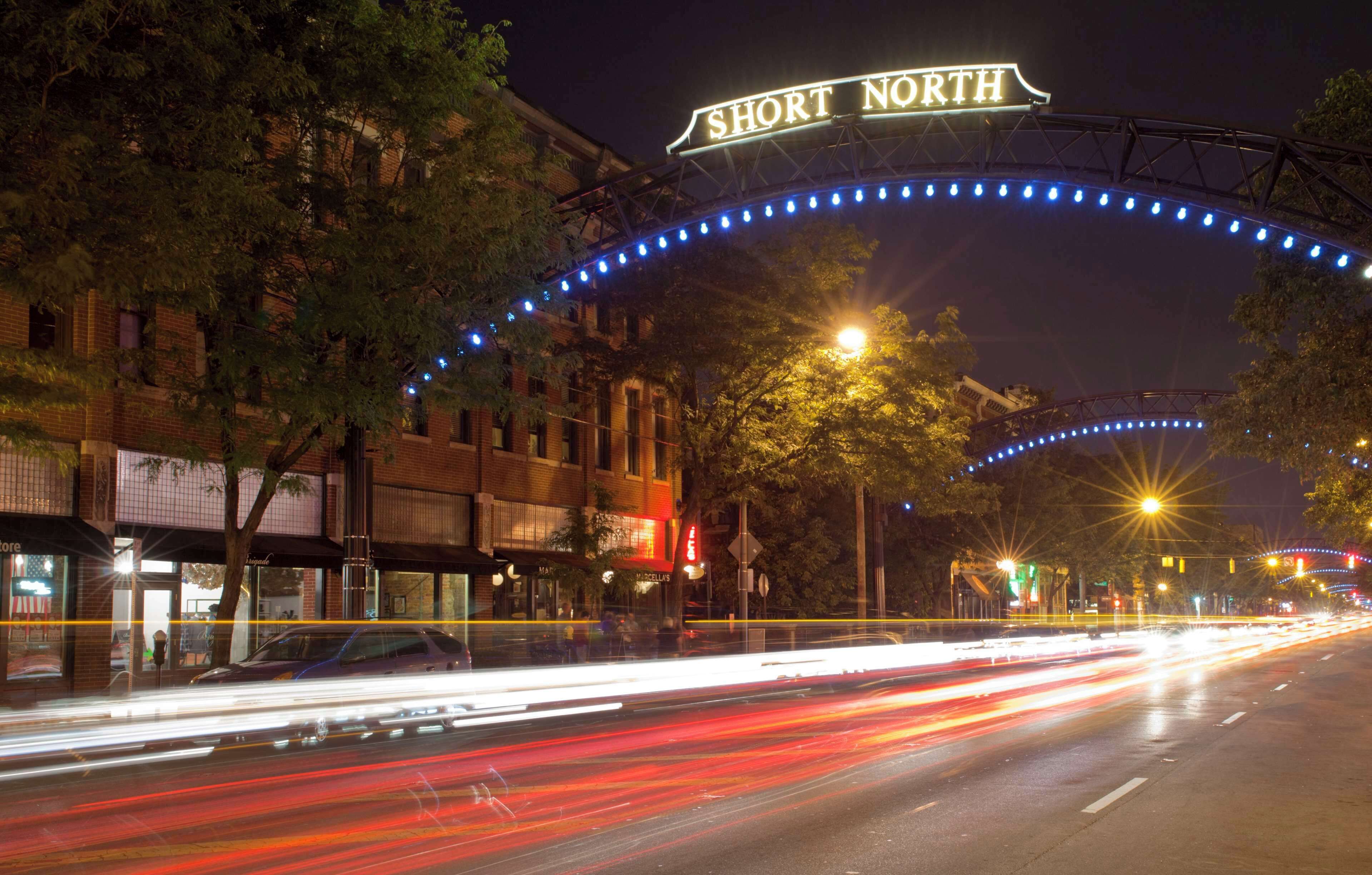 Une scène de rue avec une enseigne indiquant « SHORT NORTH » et une installation lumineuse bleue incurvée au-dessus.
