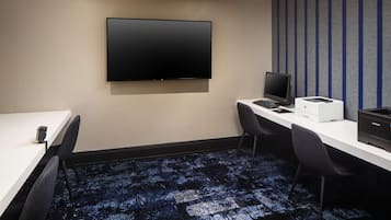 A conference room with a flat-screen TV, a desktop computer, a printer, and two chairs.