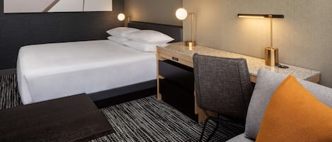 Une chambre d’hôtel avec un lit, un bureau, une chaise et une table.