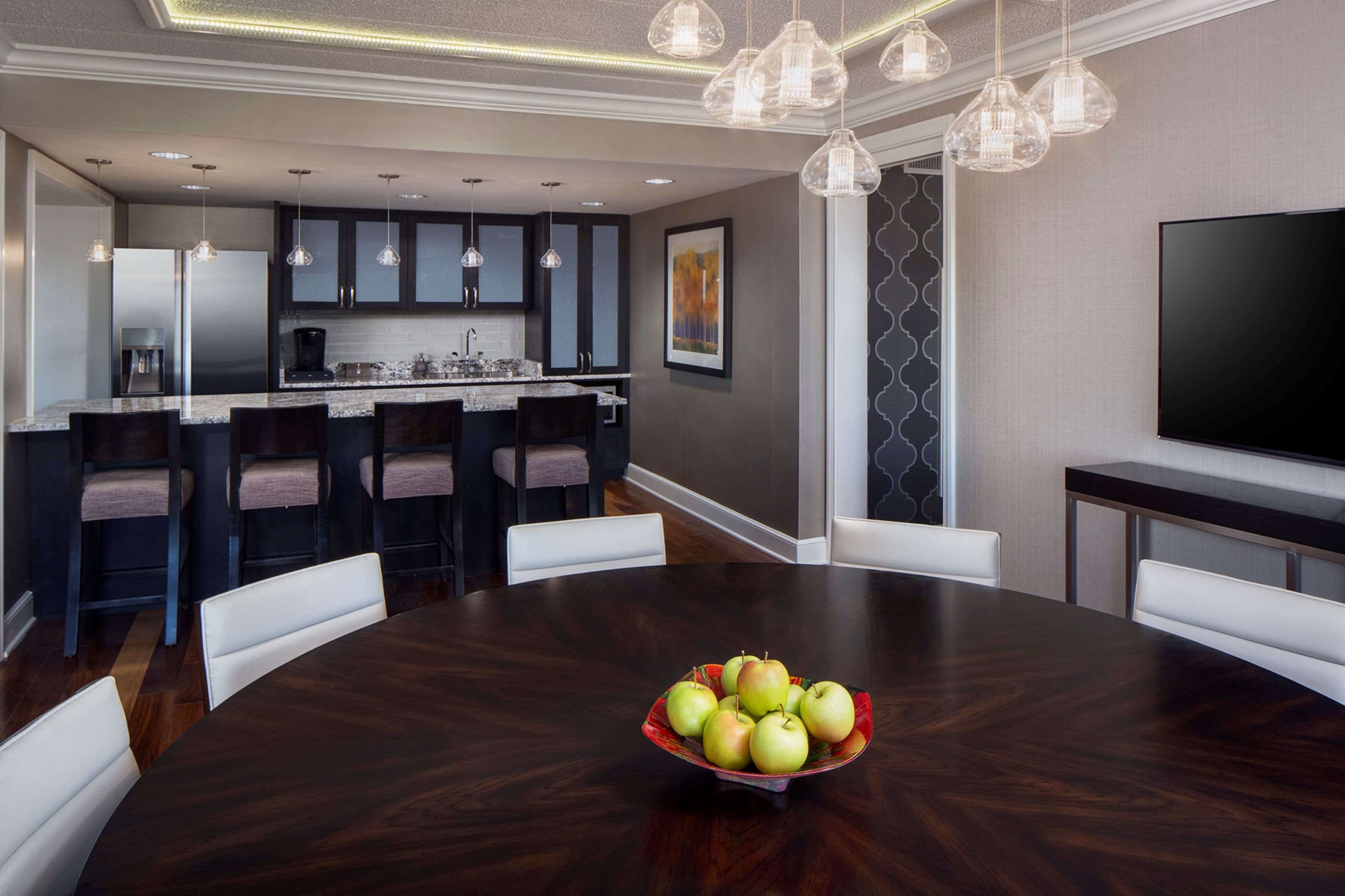 A modern kitchen with dark cabinets, a central island, and pendant lighting.