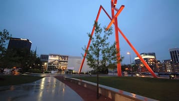 Une sculpture moderne dans un parc urbain, avec un bâtiment en arrière-plan.