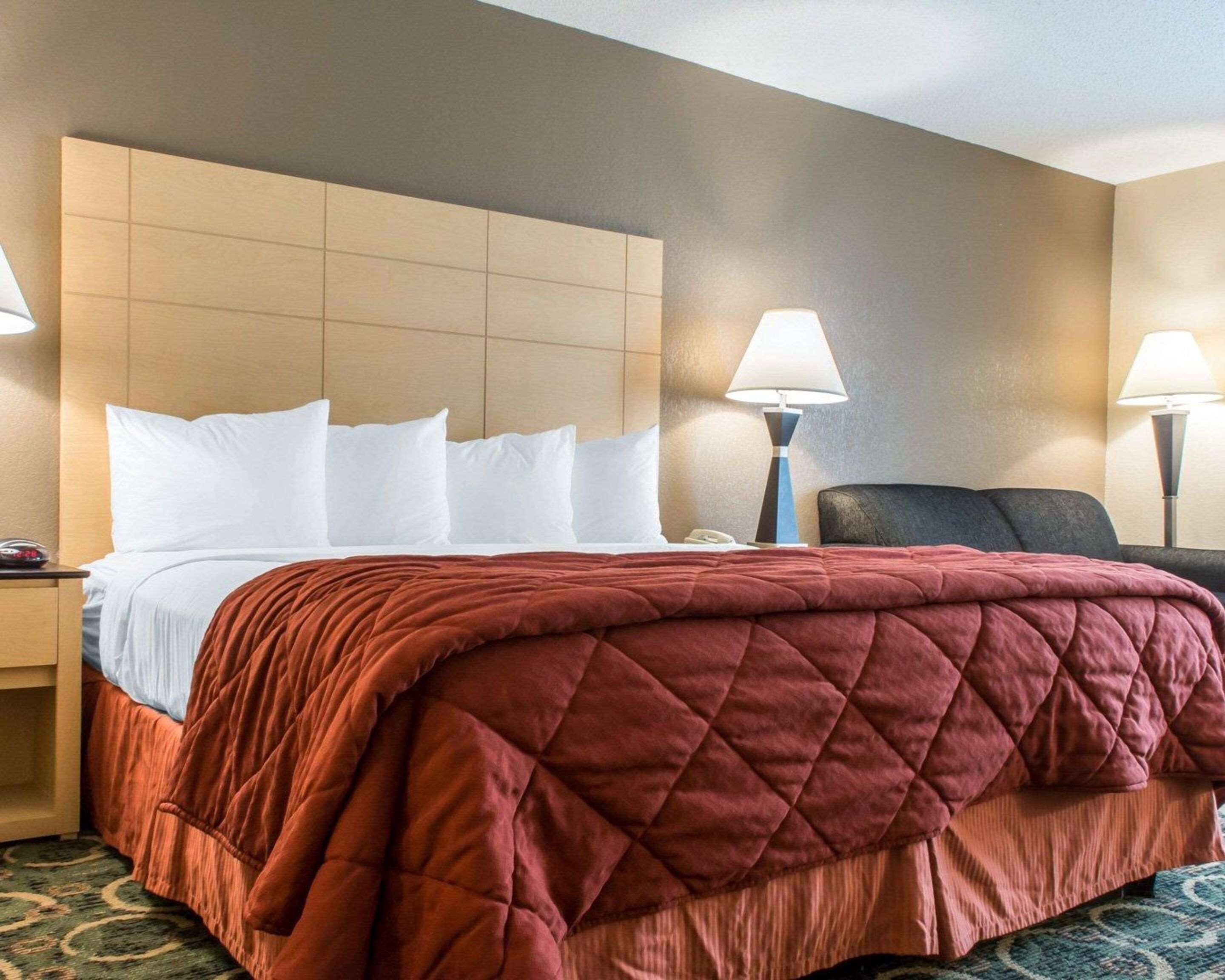Una habitación de hotel con una cama, dos lámparas de noche, una mesita de noche y una silla.