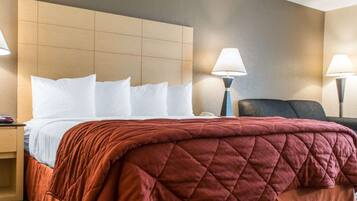 Una habitación de hotel con una cama, dos lámparas de noche, una mesita de noche y una silla.