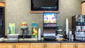 A self-service beverage station with a coffee machine, a TV screen, and a fruit bowl. - Quality Inn Geneseo (Geneseo)