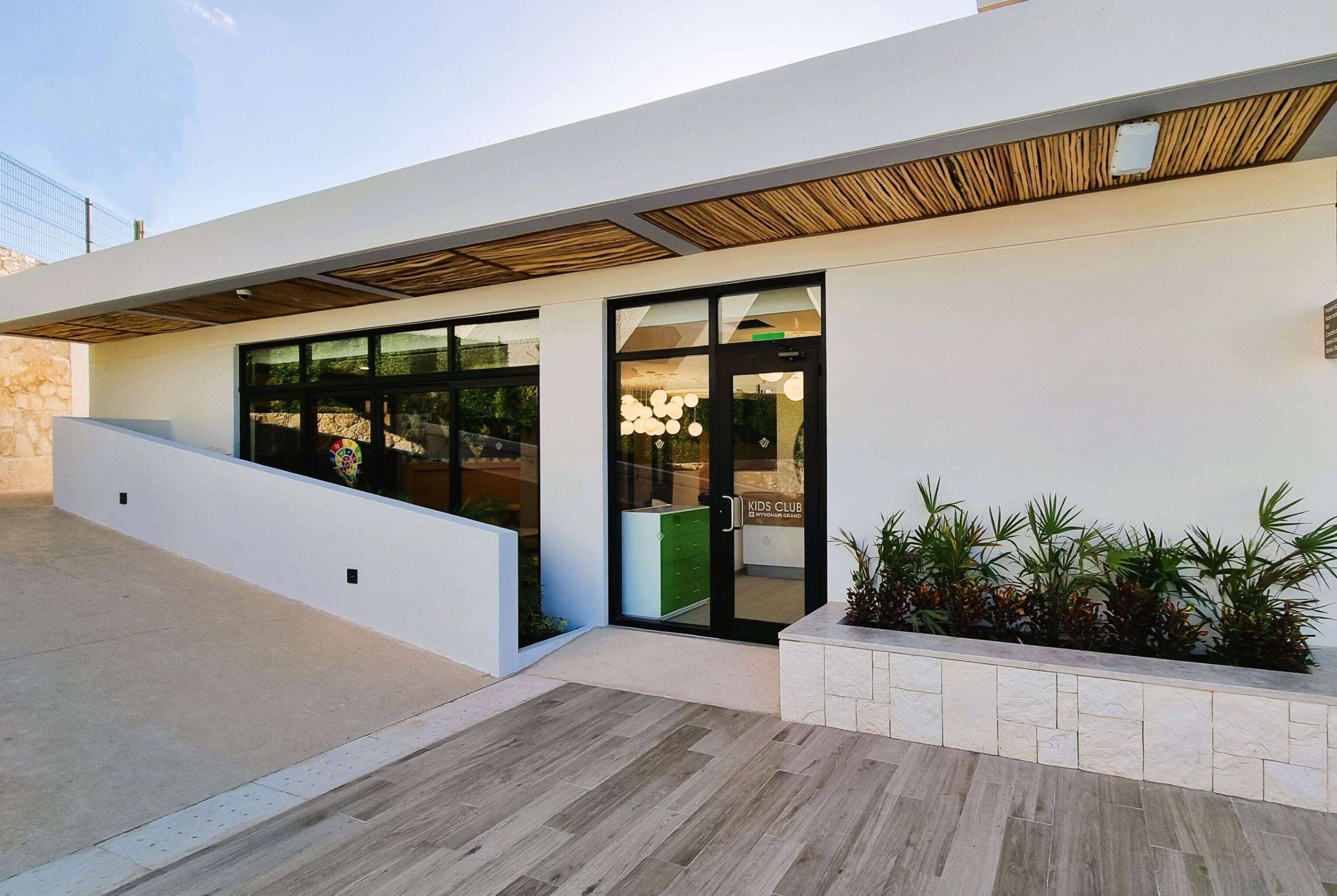 Un edificio moderno con ampie vetrate, un soffitto in legno e un'area verde con piante.