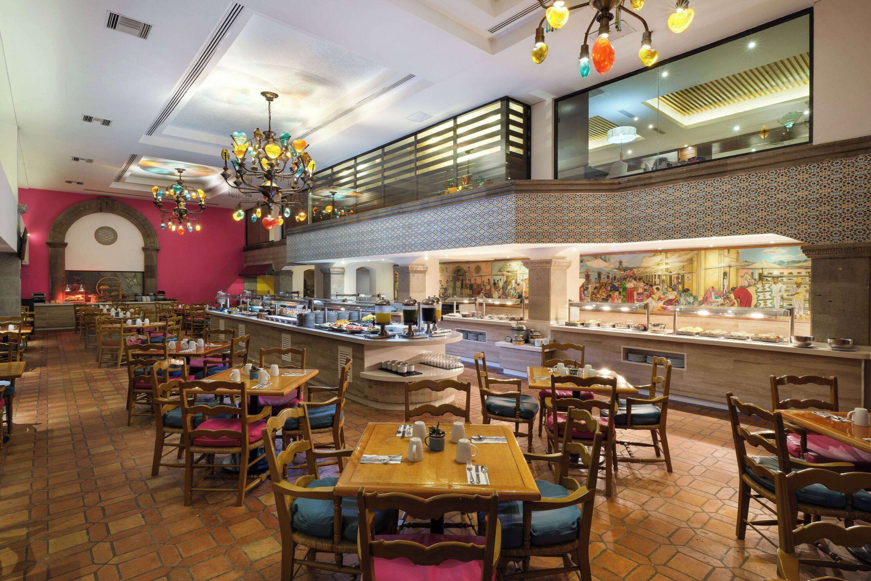 Un restaurante con varias mesas y sillas, una zona de bufé y una lámpara decorativa.