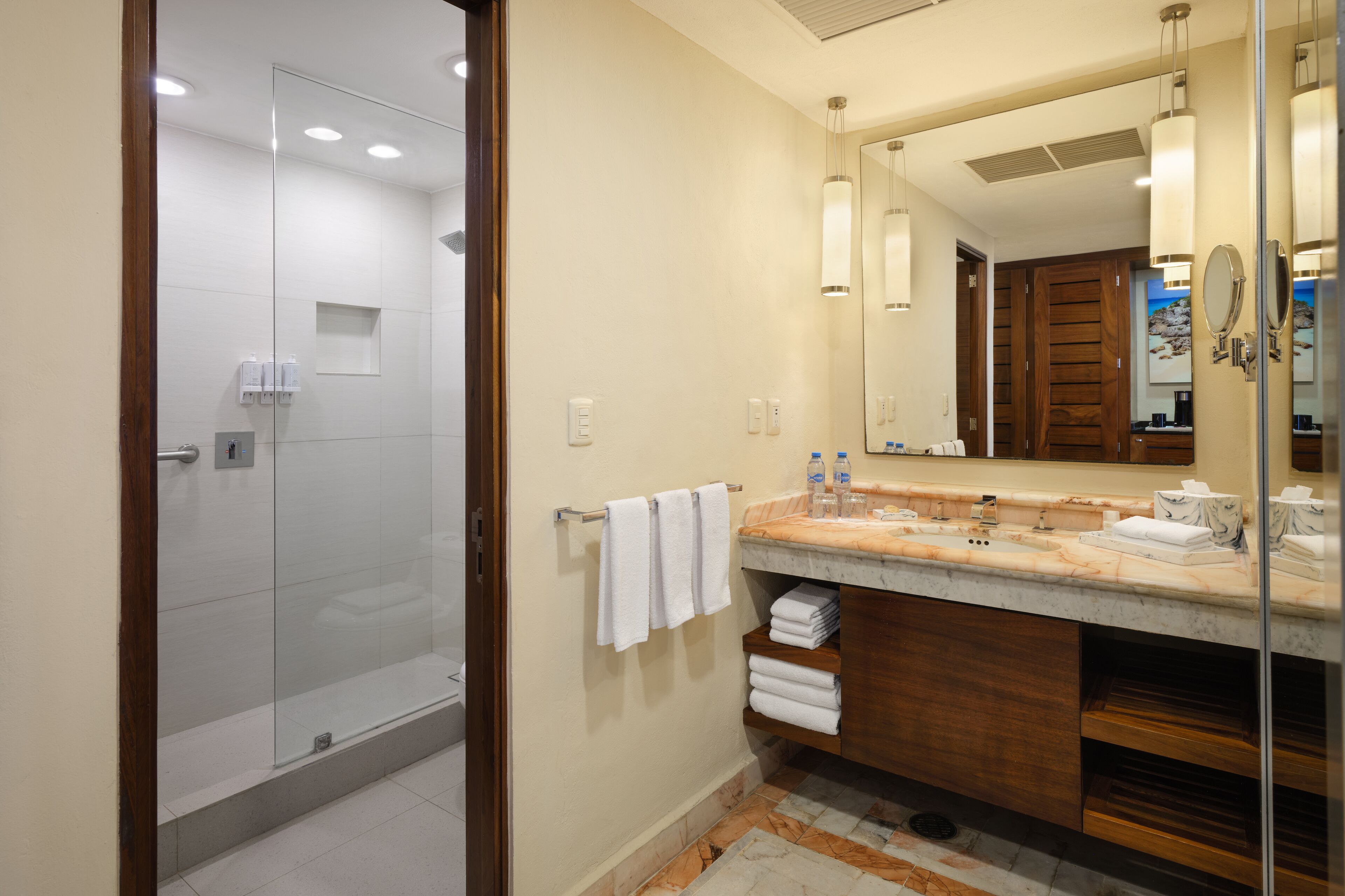 A modern bathroom with a glass shower enclosure, a marble vanity, and a large mirror.