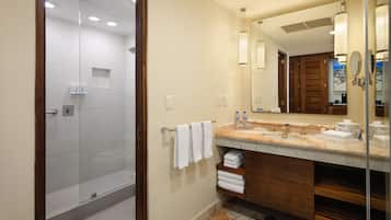 A modern bathroom with a glass shower enclosure, a marble vanity, and a large mirror.