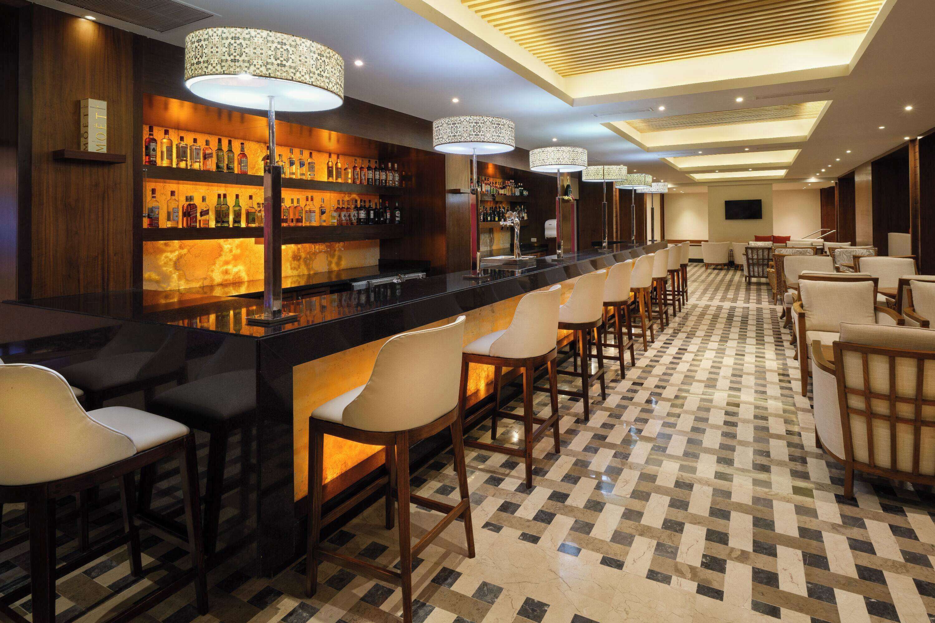 A bar area with a long counter, multiple bar stools, and a checkered floor.