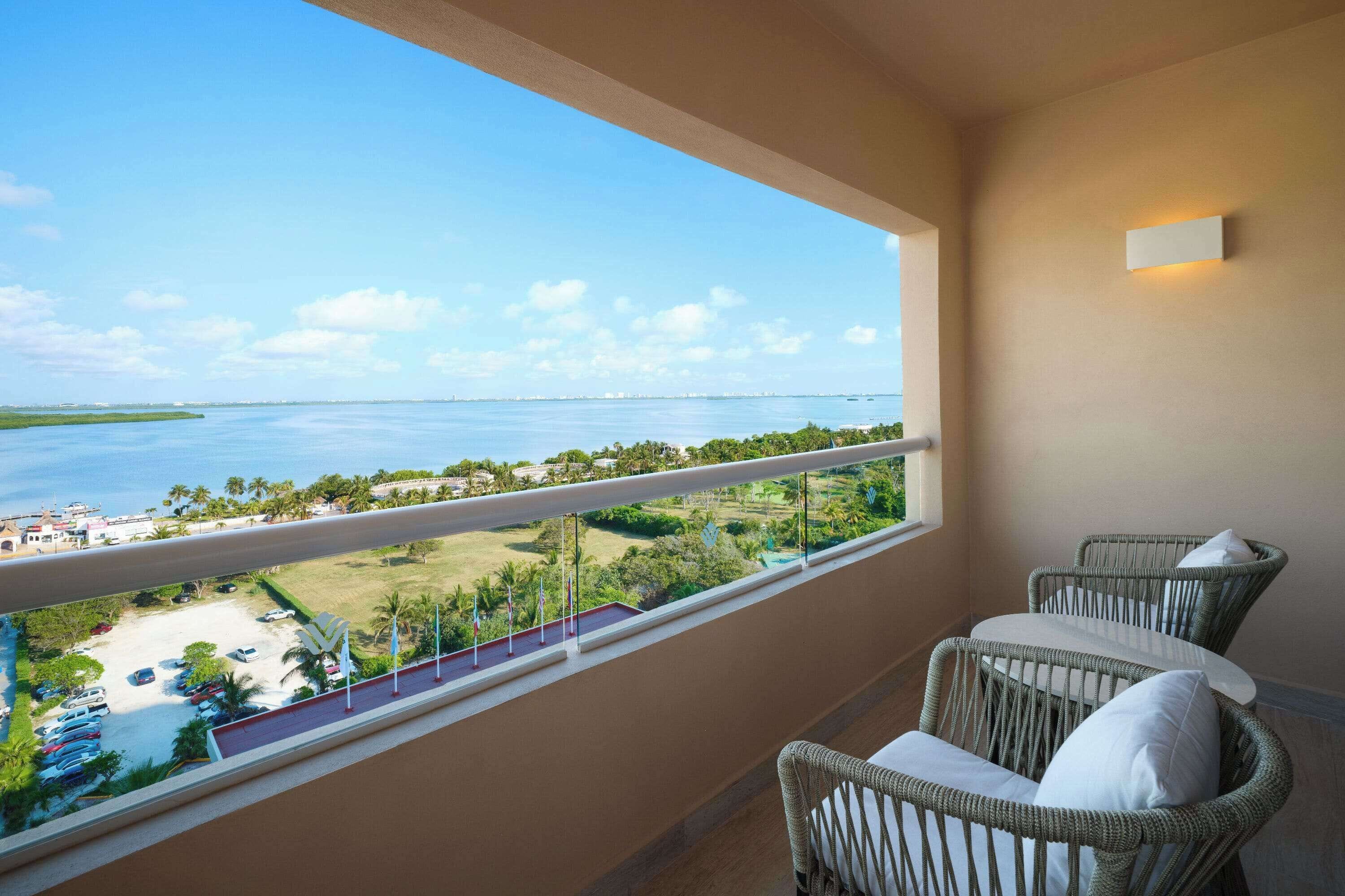 Un balcon avec des fauteuils en osier et une vue sur une plage et la mer.
